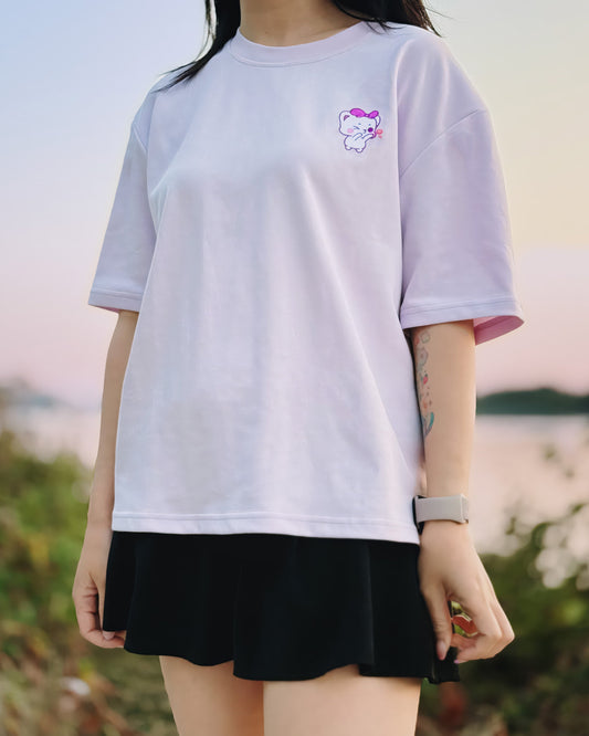 Person wearing a white t-shirt with a small graphic and a black skirt outdoors.