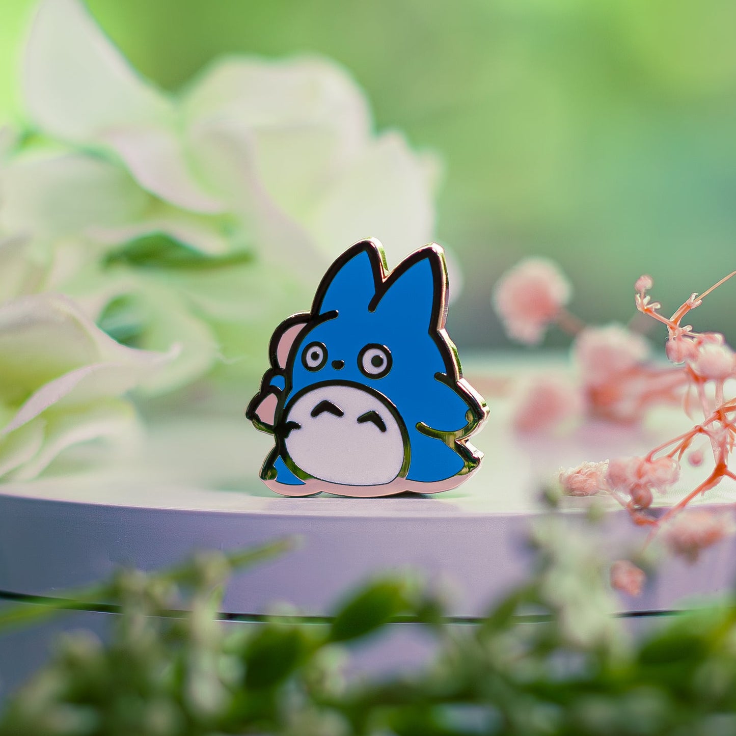 Blue cartoon character pin on a green leafy background