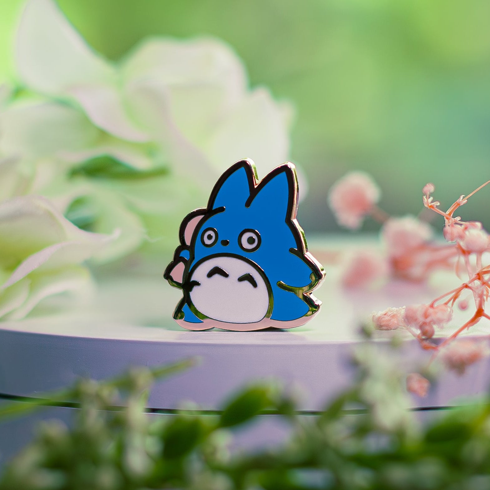 Blue cartoon character pin on a green leafy background